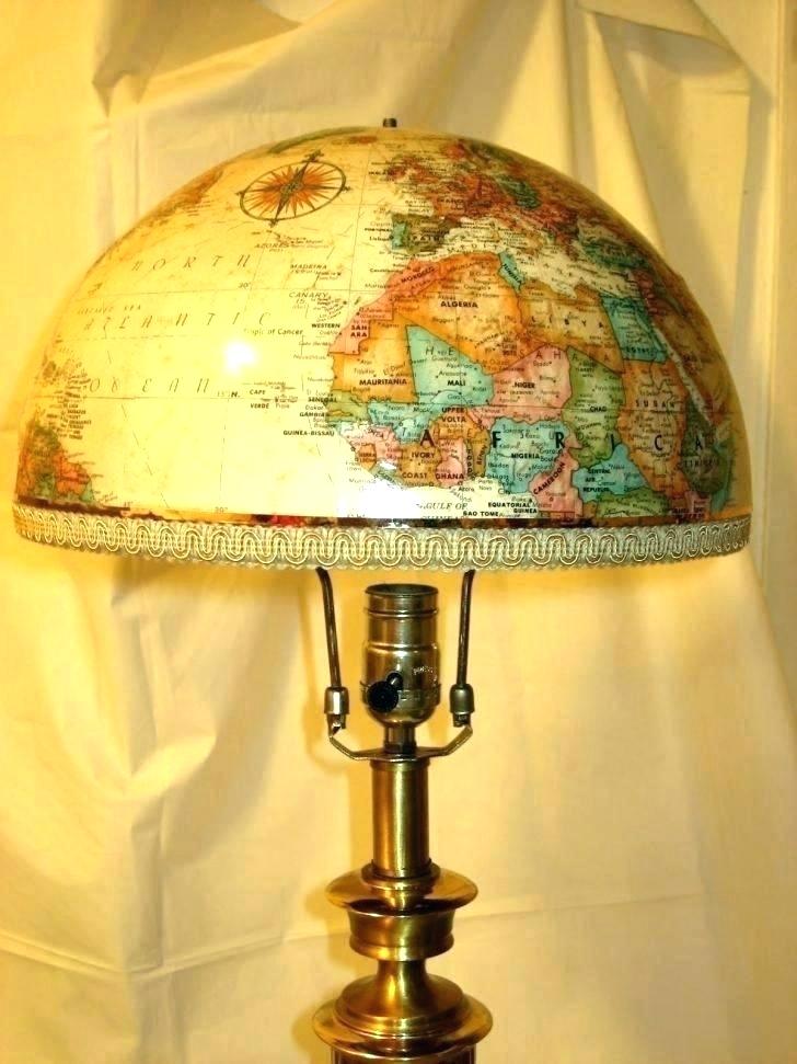 Table lamp with a dome-shaped shade decorated with a colorful world map design, brass base, soft warm lighting